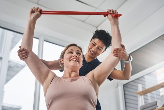 Female client undergoing resistance band training with physiotherapist