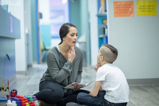 Female NDIS speech therapist works with young boy