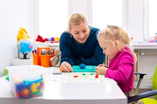 Toddler girl in child occupational therapy session doing sensory playful exercises with her NDIS key worker