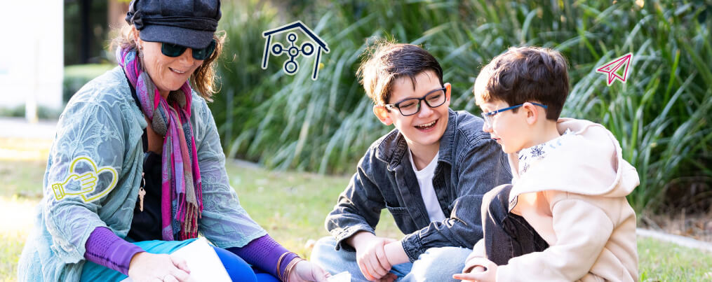 A woman and two children sitting on a lawn having fun